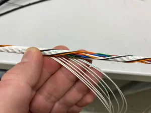 Concentric twisting a motorsport wiring bundle by hand — alternating twist directions build a round, tight loom